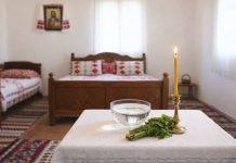 Masă pregătită pentru sfințirea casei cu lumânare aprinsă și vas cu apă sfințită