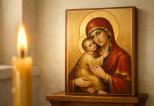Icoană a Maicii Domnului cu lumânare aprinsă într-un colț de biserică