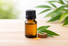 Flacon cu ulei esențial din arbore de ceai pe fundal natural