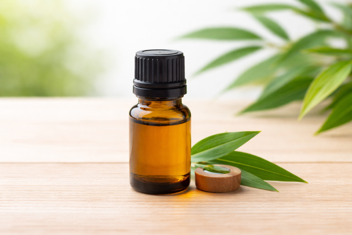 Flacon cu ulei esențial din arbore de ceai pe fundal natural