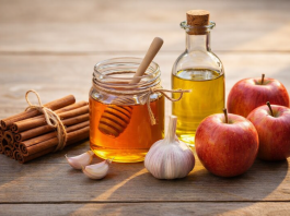 Femeia care a trăit peste 100 de ani spune: „Dacă vrei o viață lungă, mănâncă regulat aceste 5 alimente” Scorțișoară, miere, usturoi, ulei de măsline și mere așezate pe o masă rustică