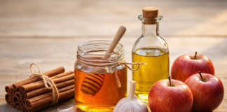 Femeia care a trăit peste 100 de ani spune: „Dacă vrei o viață lungă, mănâncă regulat aceste 5 alimente” Scorțișoară, miere, usturoi, ulei de măsline și mere așezate pe o masă rustică