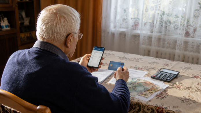 pensii-card-iulie-2026.jpg Pensionar verificând banii primiți pe card după virarea pensiei în luna iulie 2026