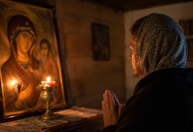 Persoană rugându-se în fața unei icoane, într-o cameră liniștită, căutând pace sufletească